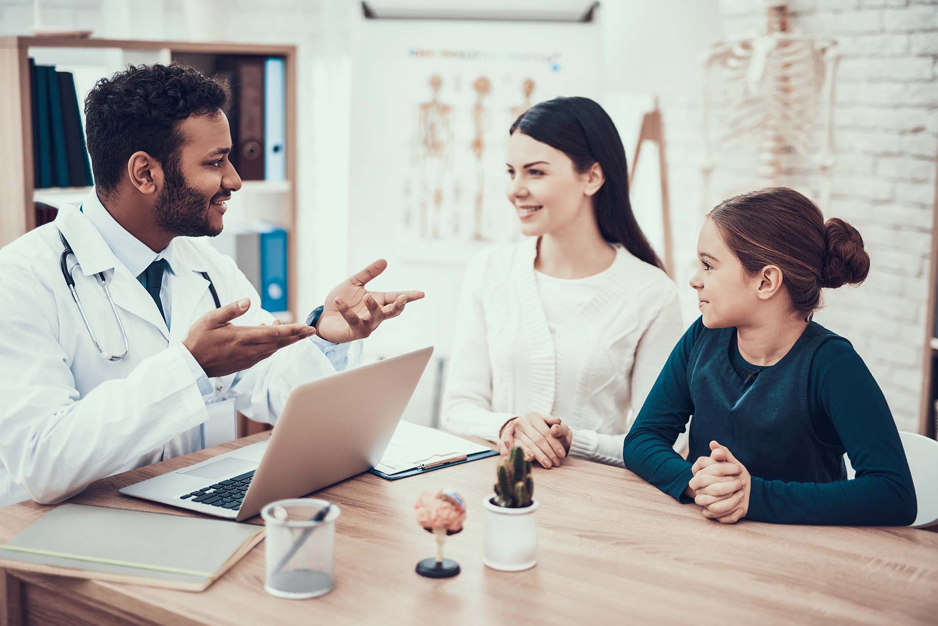 Doctor in white jacket seeing a mother and daughter in office.