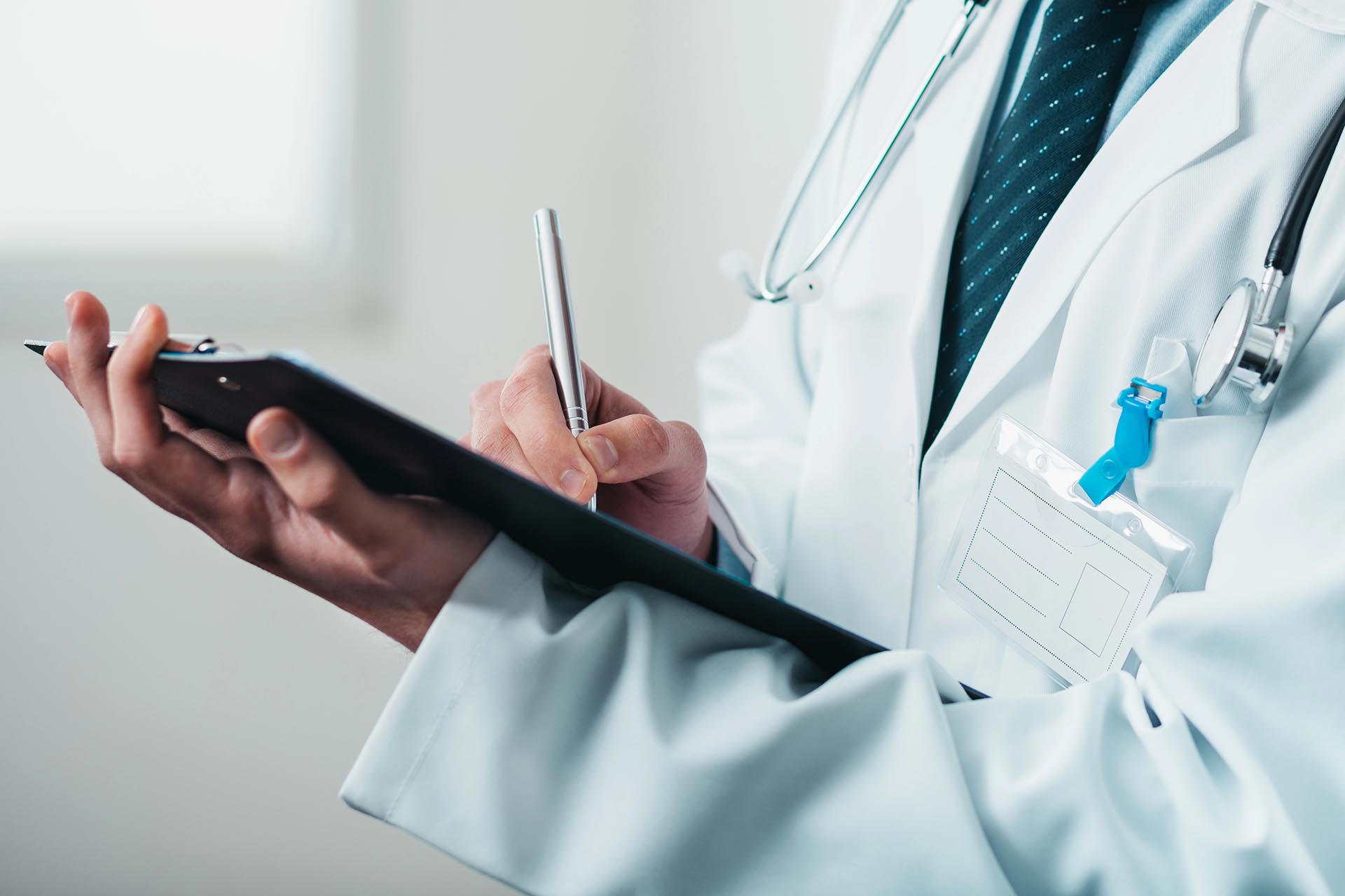 Detail of doctor's hand writing down prescription on a clipboard