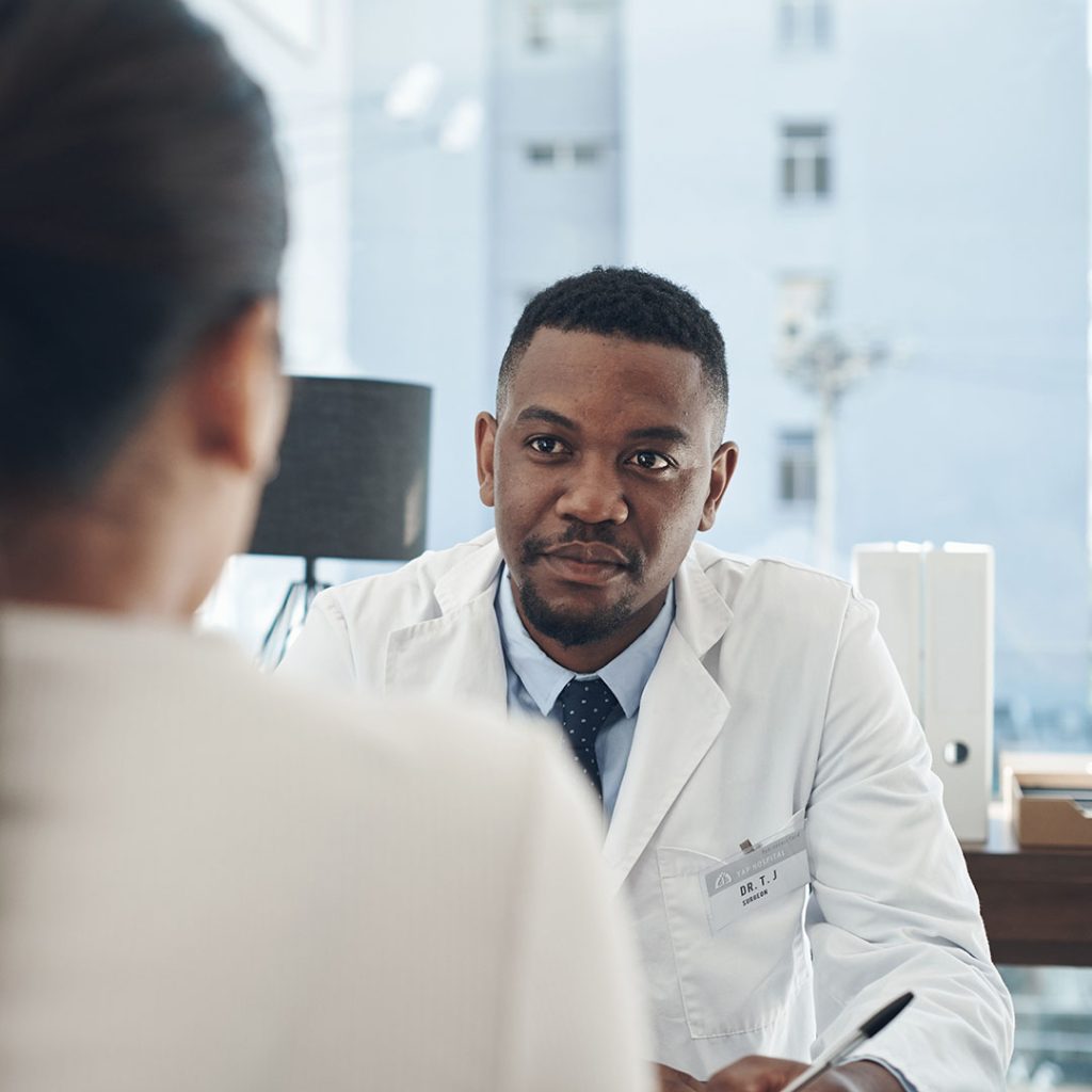 A young male doctor talking to a patient in an office.